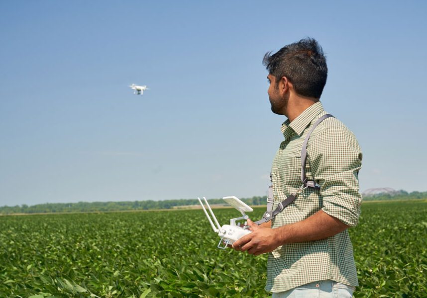 Man flying drone over a green field